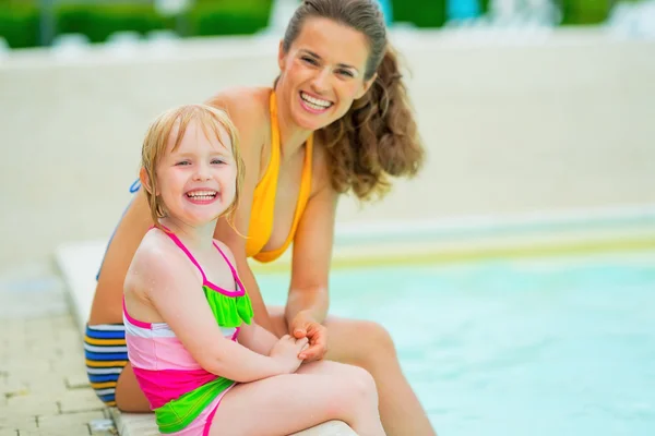 Retrato de madre feliz y niña sentada junto a la piscina —  Fotos de Stock