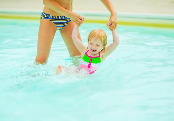 Mother and baby girl playing in pool — Stock Photo, Image