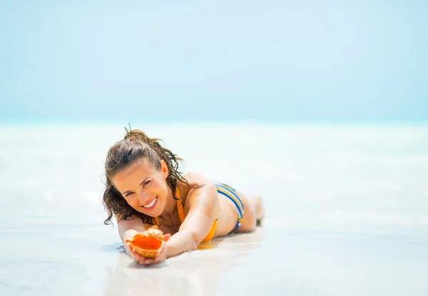 Young woman with shell laying on sea shore — Stock Photo, Image