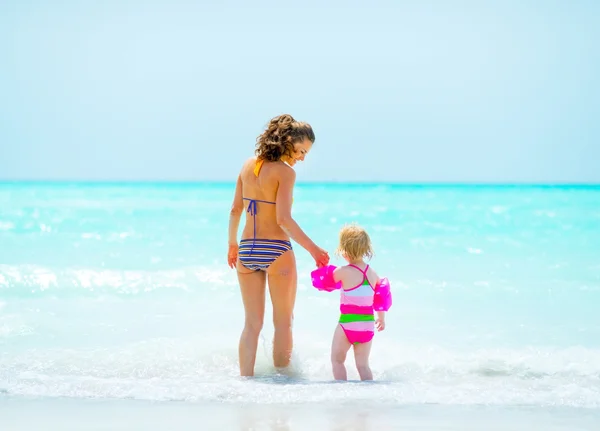 Mother and baby girl going into sea. rear view — Stock Photo, Image