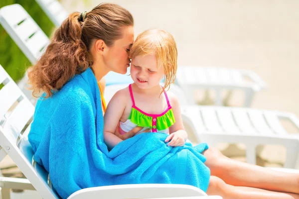 Mother and baby girl wrapped in towel sitting on sunbed — Stock Photo, Image