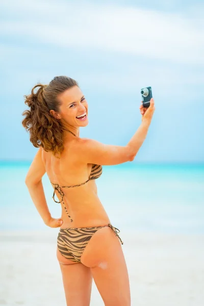 Hymyilevä nuori nainen tekee selfie rannalla — kuvapankkivalokuva
