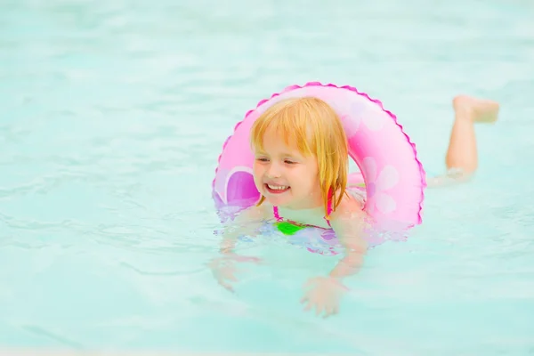 Happy baby girl with swim ring swimming in pool — Stock Photo, Image