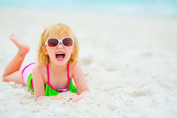 Retrato de niña feliz en gafas de sol colocadas en la playa —  Fotos de Stock