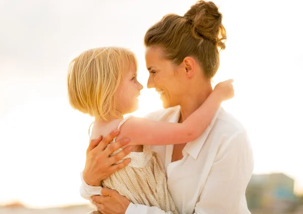 Porträt einer glücklichen Mutter und eines kleinen Mädchens, die sich am Strand am Meer umarmen — Stockfoto