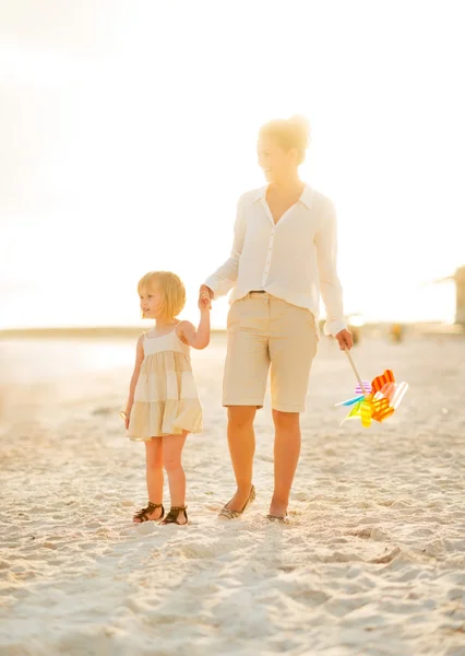 Mor og baby pige går på stranden om aftenen - Stock-foto