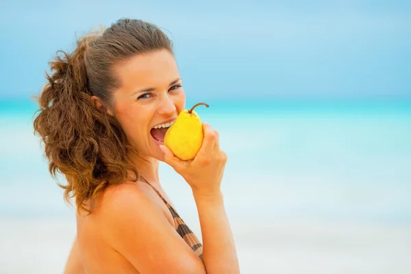 Retrato de una joven comiendo pera en la playa —  Fotos de Stock