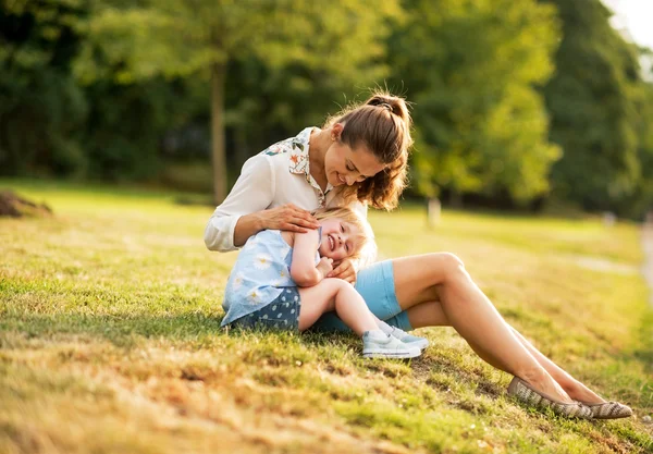 Mor og baby pige sidder udendørs om aftenen - Stock-foto