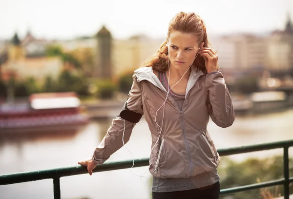 Mujer joven fitness en los auriculares en la ciudad por la noche — Foto de Stock