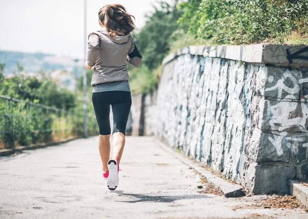 在城市公园慢跑健身的年轻女人。后方的看法 — 图库照片