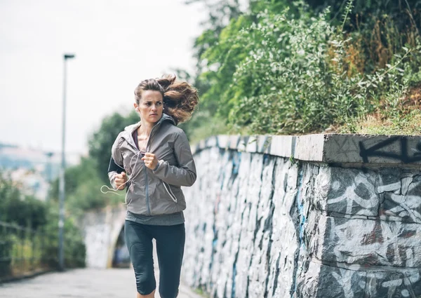 Фитнес-молодая женщина бегает в городском парке — стоковое фото