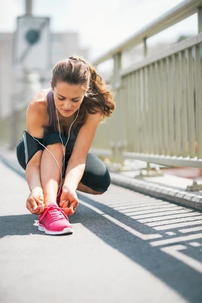 Fitness young woman tying shoelaces in the city — Stock Photo, Image