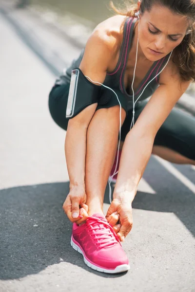 Fitness young woman tying shoelaces outdoors — Stock Photo, Image