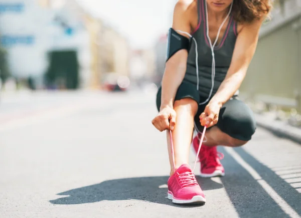 Gros plan sur fitness jeune femme attachant lacets dans la ville — Photo
