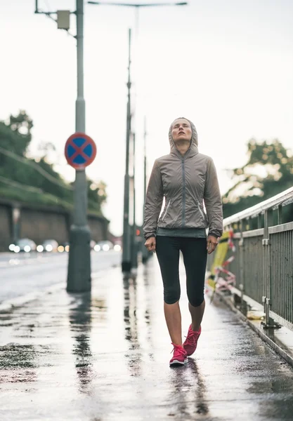 Retrato de fitness mulher jovem andando na cidade chuvosa — Fotografia de Stock