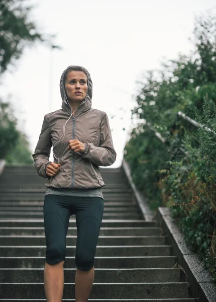 Fitness joven mujer corriendo en la ciudad lluviosa — Foto de Stock