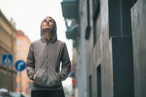 Retrato de la mujer joven fitness de pie cerca del edificio en lluvia — Foto de Stock