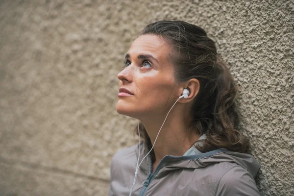 Portret van fitness jonge vrouw luisteren muziek buitenshuis — Stockfoto