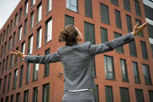 Donna d'affari che si rallegra davanti all'edificio degli uffici. vista posteriore — Foto Stock