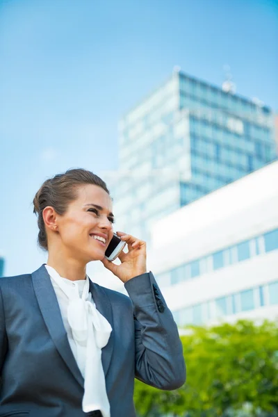 Smiling business woman talking mobile phone in office district — Stok fotoğraf