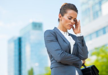 Stressed business woman with briefcase in office district