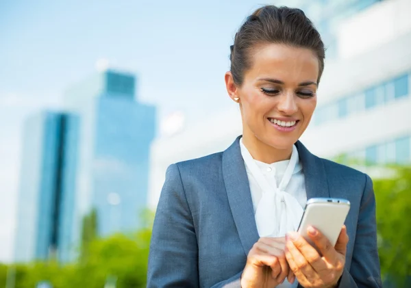 Feliz mujer de negocios escribiendo sms en el distrito de oficina —  Fotos de Stock