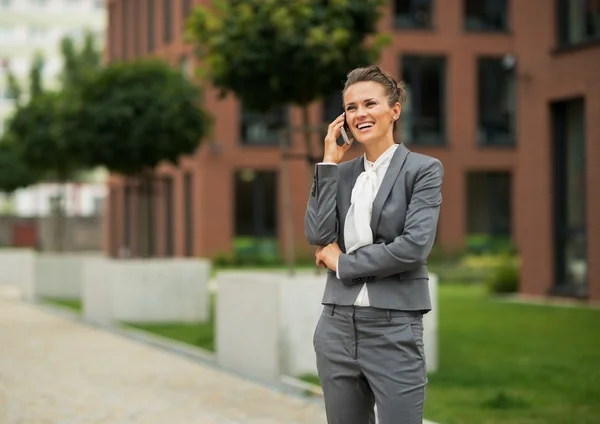 Happy business woman talking cell phone in front of office build — Stockfoto
