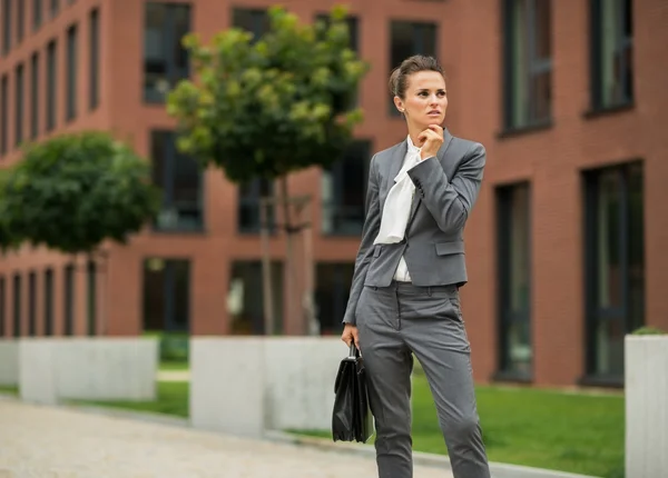 Thoughtful business woman with briefcase in front of office buil — Stock Photo, Image