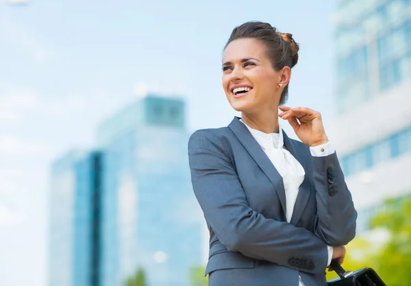 Mujer de negocios sonriente con maletín en el distrito de oficina buscando — Foto de Stock