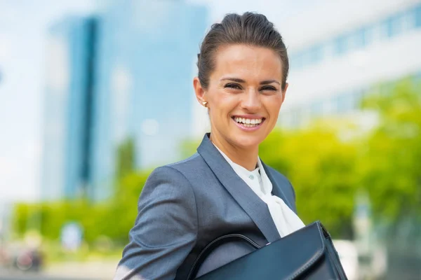 Portrait of smiling business woman with briefcase in office dist — ストック写真