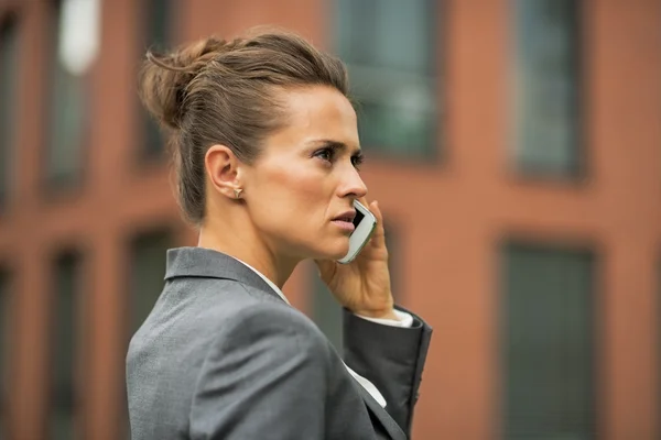 Grave donna d'affari parlando cellulare di fronte ufficio bui — Foto Stock