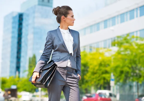 Happy business woman with briefcase in office district looking o — Stockfoto