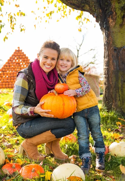 Porträt einer glücklichen Mutter und eines Kindes mit einem Kürbis — Stockfoto