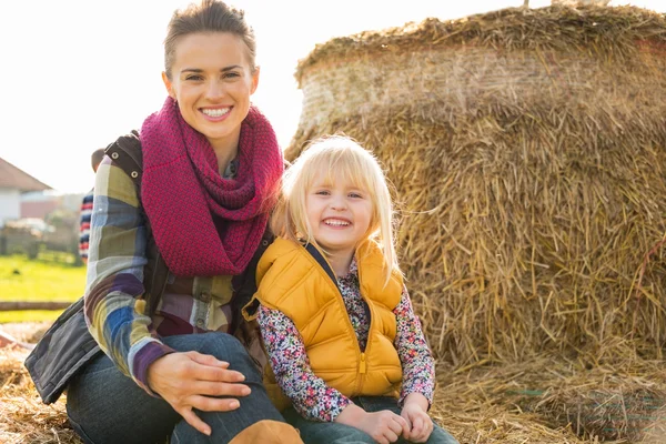 Portret van gelukkige moeder en kind zittend op hooiberg — Stockfoto