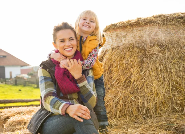 Портрет улыбающейся матери и ребенка, сидящих на стоге сена — стоковое фото
