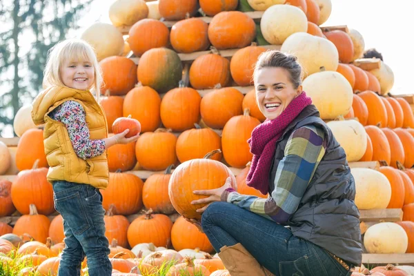 Портрет счастливой матери и ребенка, выбирающих тыквы — стоковое фото