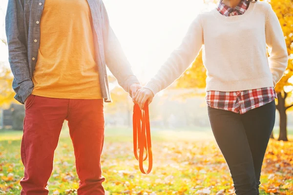 Gros plan sur jeune couple tenant la laisse ensemble dans le parc d'automne — Photo