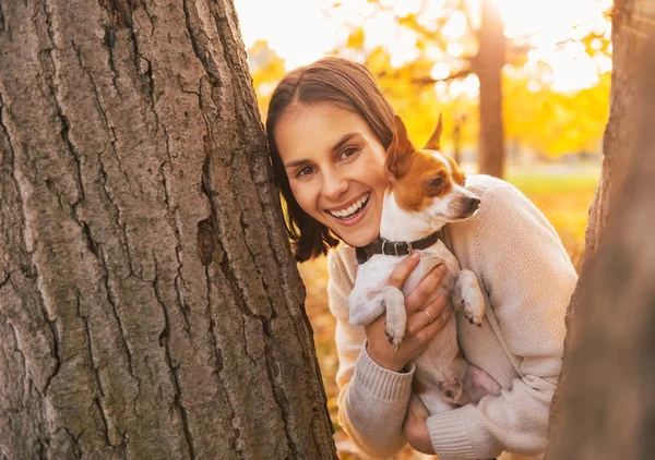 F 外を見て秋の公園で屋外の犬と幸せな若い女 — ストック写真