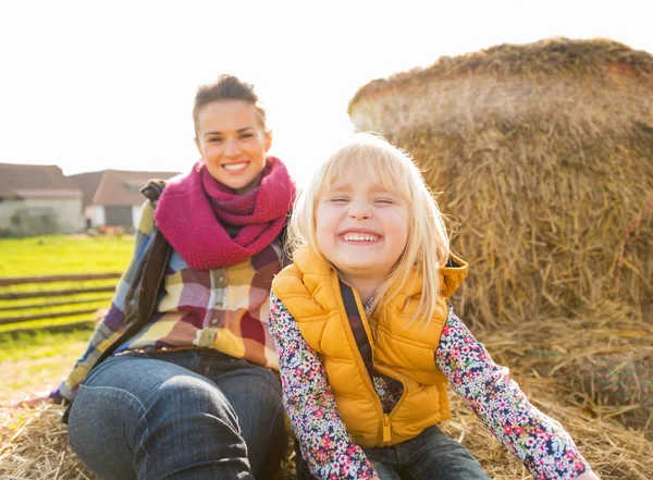 Porträt einer lächelnden Mutter und eines Kindes auf einem Heuhaufen — Stockfoto