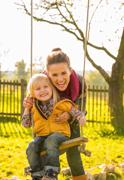 Porträt einer lächelnden Mutter und eines Kindes auf einer Schaukel — Stockfoto