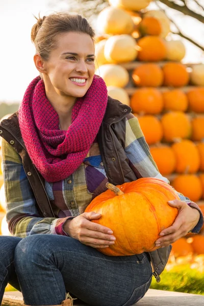 Portrait of happy young woman sitting with pumpkin in front of p — Stock Photo, Image