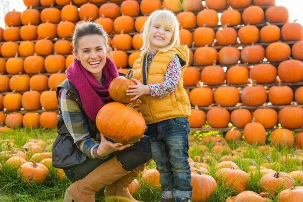 Portret van gelukkige moeder en kind kiezen pompoenen — Stockfoto