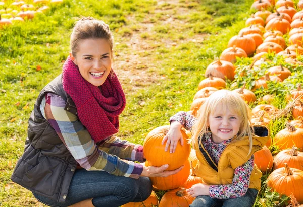 Porträt einer glücklichen Mutter und eines glücklichen Kindes inmitten eines Kürbisses — Stockfoto