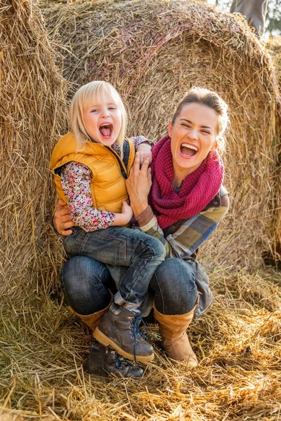Portret van moeder en kind in de buurt van hooiberg glimlachen — Stockfoto