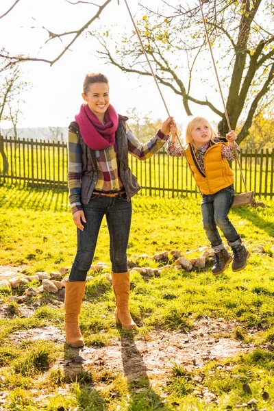 Gelukkig moeder swingende kind buiten — Stockfoto