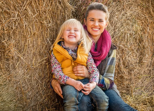 Portræt af glad mor og barn nær høstak - Stock-foto