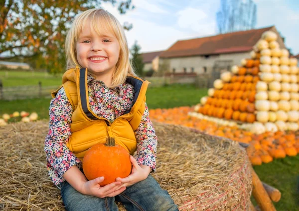かぼちゃの干し草の山の上に座って幸せな子供の肖像画 — ストック写真