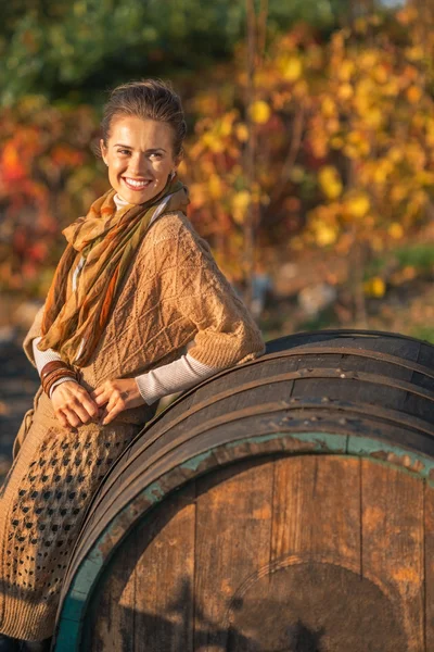 Uśmiechnięta młoda kobieta w pobliżu drewnianej beczce patrząc na miejsce — Zdjęcie stockowe
