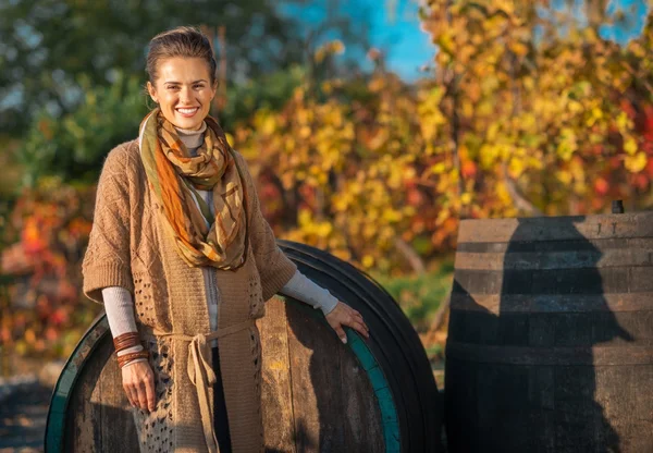 Portrait of happy young woman standing near wooden barrel in aut — Stock Photo, Image