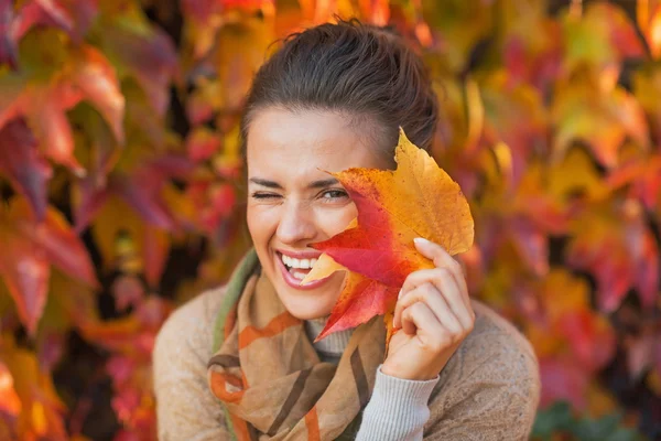Ritratto di giovane donna felice nascosta dietro foglie autunnali in fron — Foto Stock